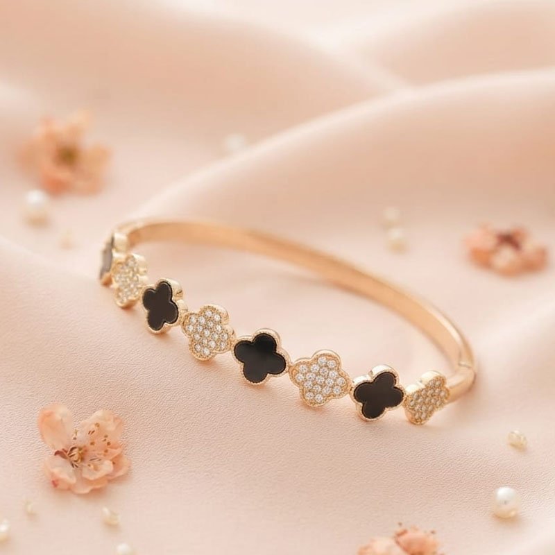 gold clover bracelet with black and crystal four leaf motifs on a satin background