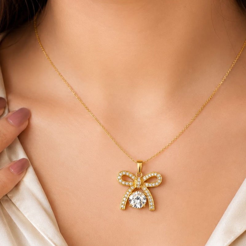gold bow necklace with crystal encrusted ribbon pendant worn on a woman's neck