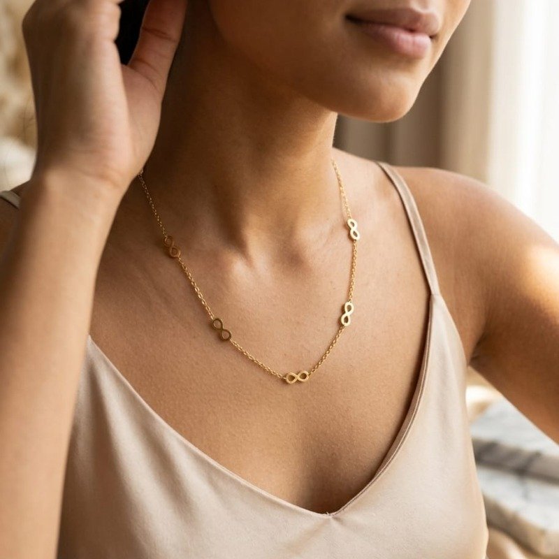 Gold infinity necklace with delicate chain design worn by a woman